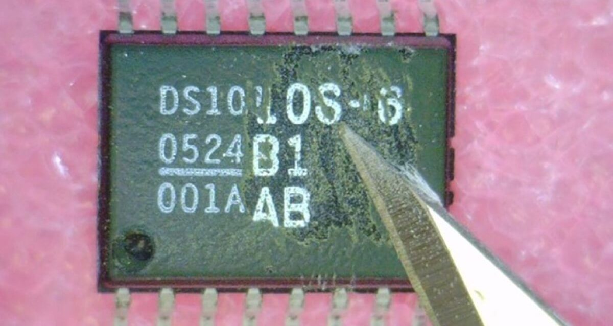 Picture of an electronic component with its serial numbers being scratched off with a scissors